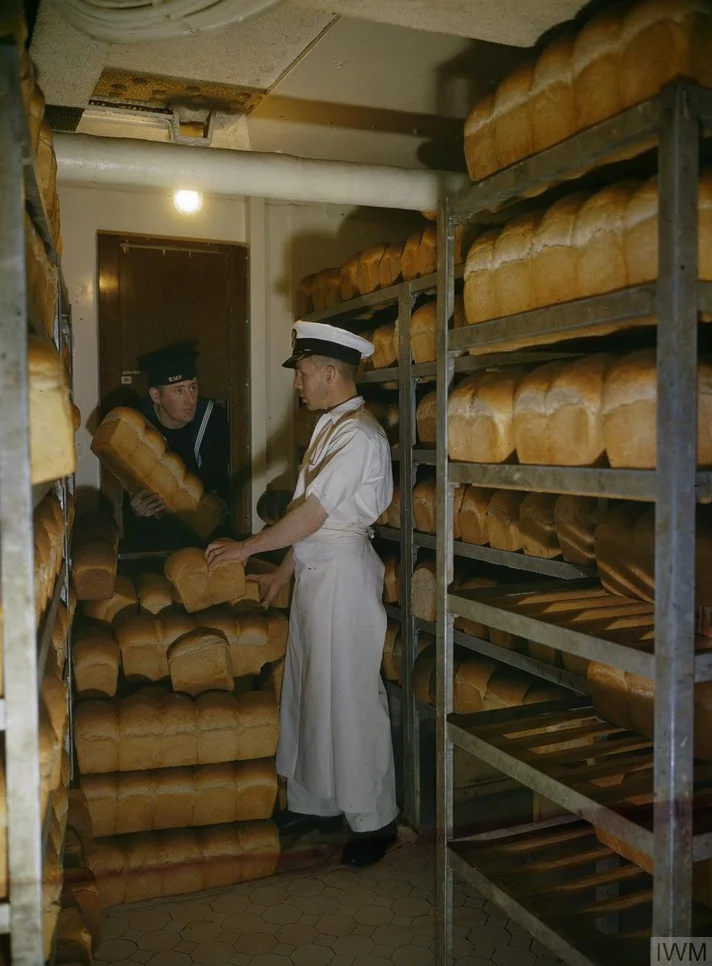 A naval rating collects bread for his mess from the battleship's bakery, November 1942..webp