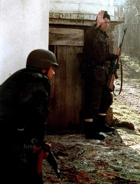 A Serbian policeman tells his colleague to take cover during a KLA attack on the village of R...webp