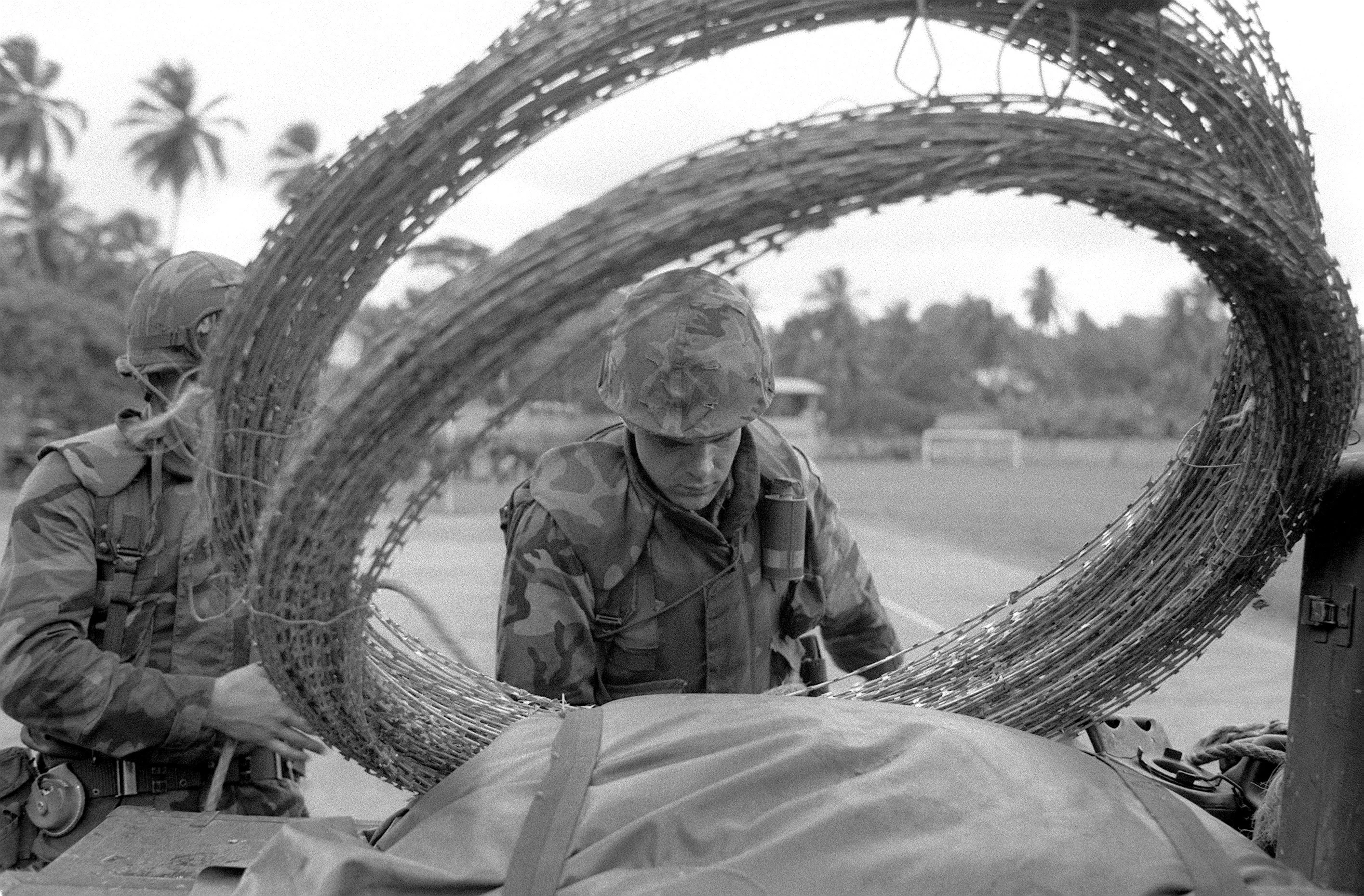 a-view-through-a-coil-of-barbed-wire-of-a-marine-as-he-replenishes-his-water-0bc186.jpg