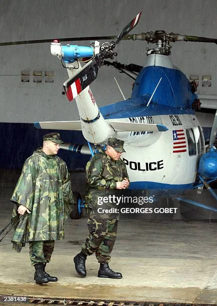 unidentified-us-military-experts-pass-in-front-of-a-liberain-police-helicopter-at-the-james.webp