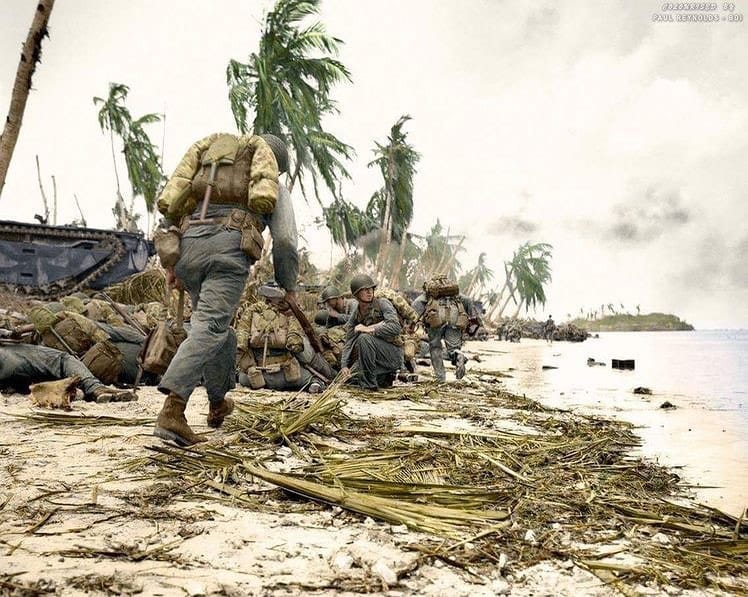 US Marines of the 3rd Marine Division take cover along the beach line shortly after landing on...jpg