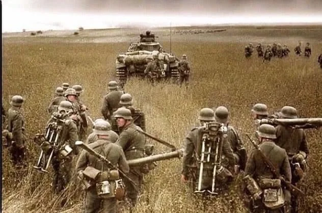 Wehrmacht troops walking through a field with a Panzer tank during the very opening days of O...webp