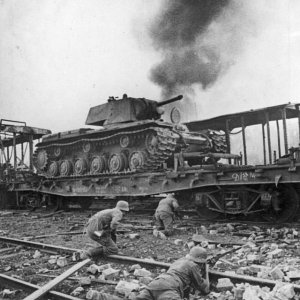 German soldiers advance through a Red Army depot with KV-1 tanks still on delivery trains in Smolensk (1941