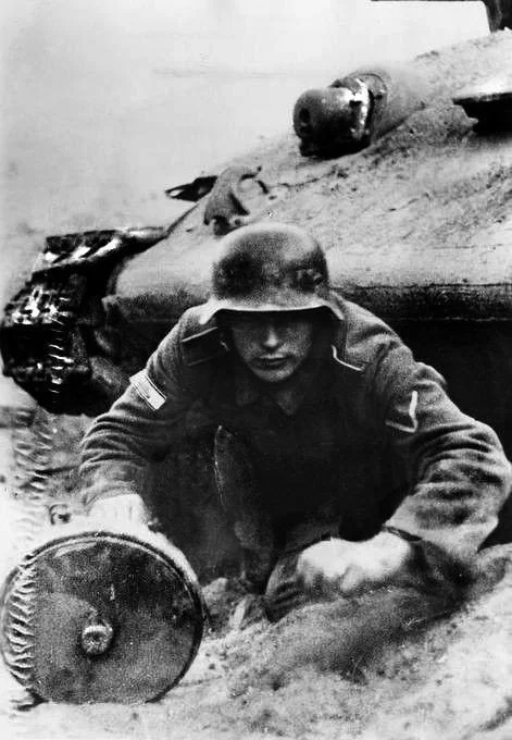 A German soldier pops out under a destroyed T-34 with a Tellermine. On his right sleeve a tank destruction badge