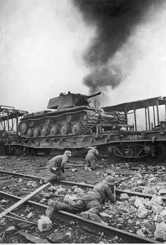 German soldiers advance through a Red Army depot with KV-1 tanks still on delivery trains in Smolensk (1941