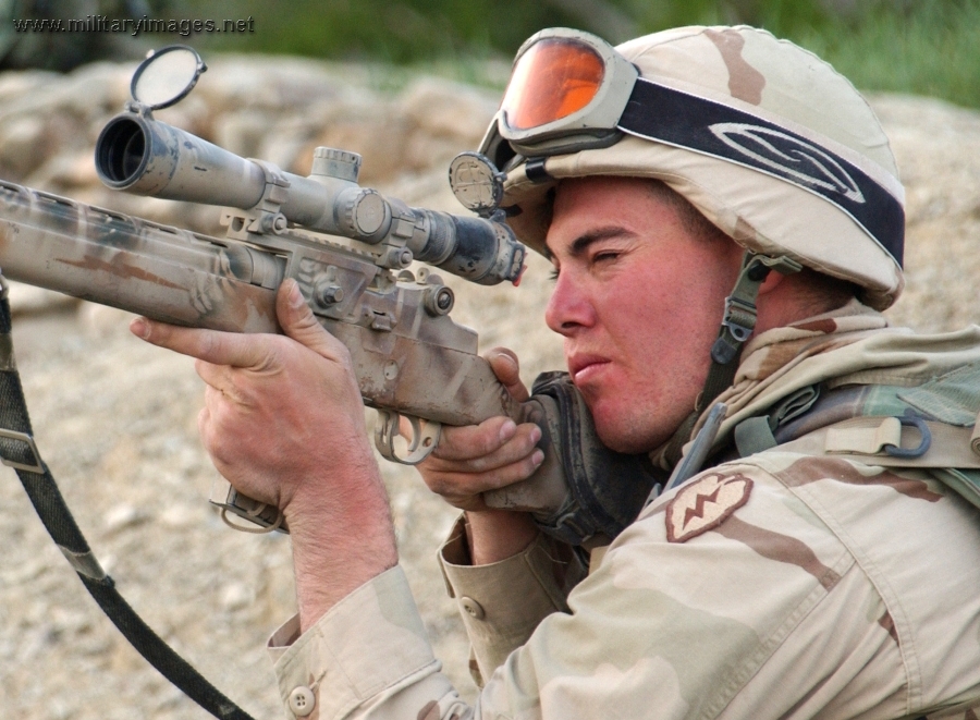 Soldier peers through the scope on his rifle